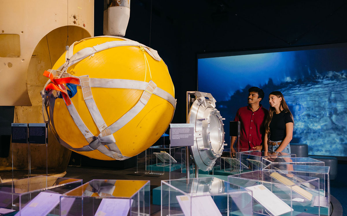 Man and a woman looking at the yellow underwater craft on display in the museum