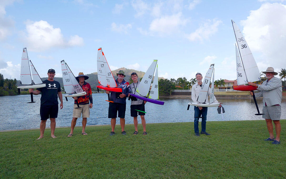 Group of men holding radio-controlled yachts