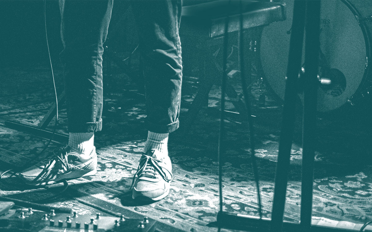 Persons feet standing near drums and mic equipment