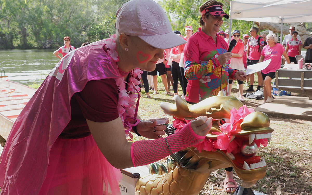 Woman wearing pink, painting a gold dragon