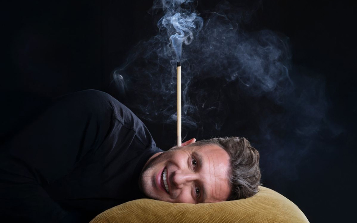 Tommy Little smiling with ear candle in his ear.