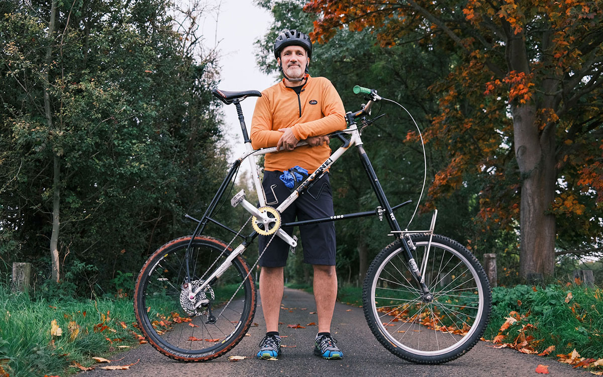 Man in orange jacket and helmet standing in front of his bike
