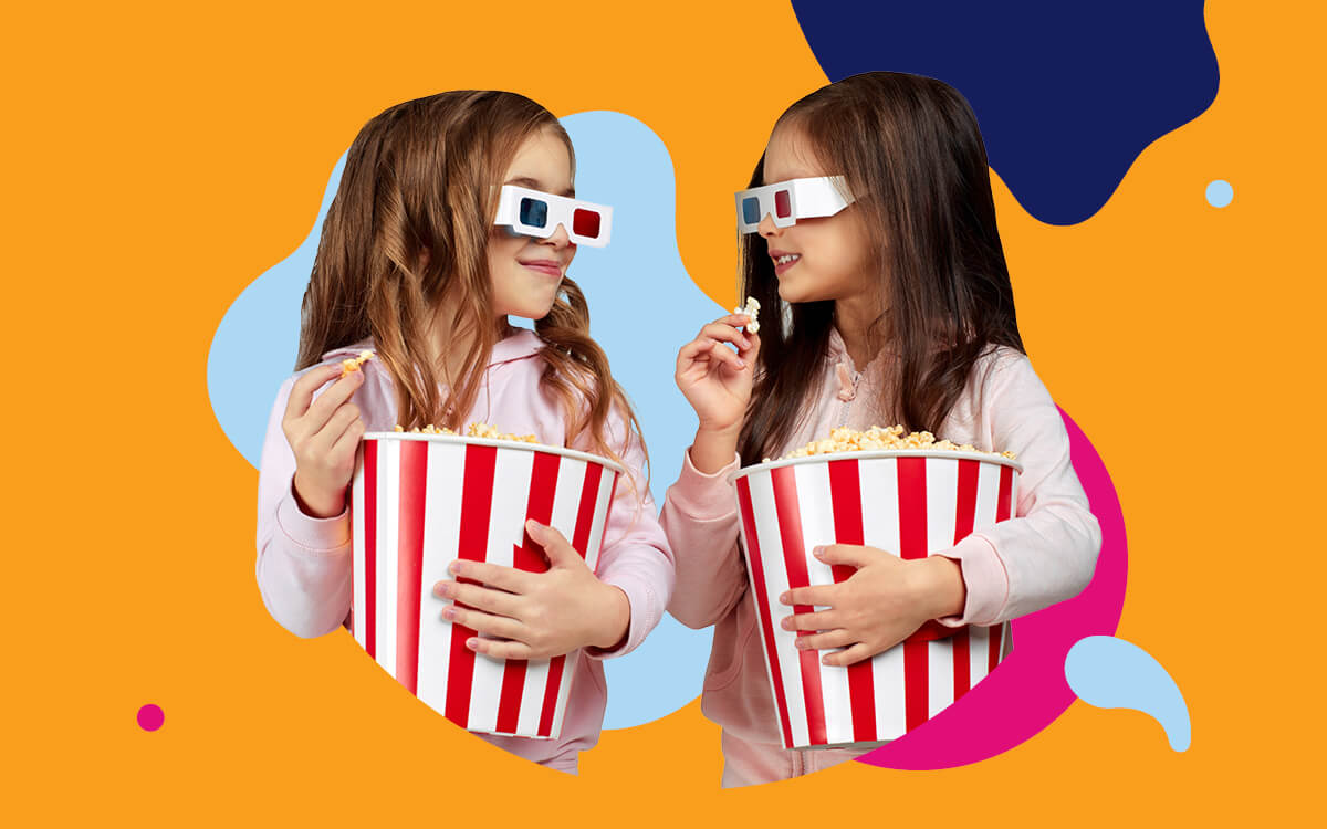 Two girls wearing 3D glasses and holding buckets of popcorn 