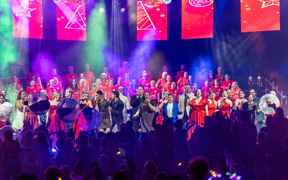 Carols by Candlelight event with people singing and audience watching