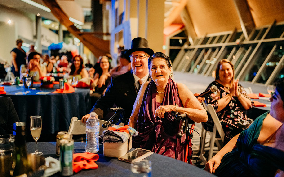 Man in a top hat sitting with a woman at a table at a ball