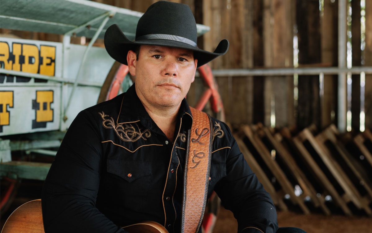 Male performer wearing a cowboy hat and holding a guitar