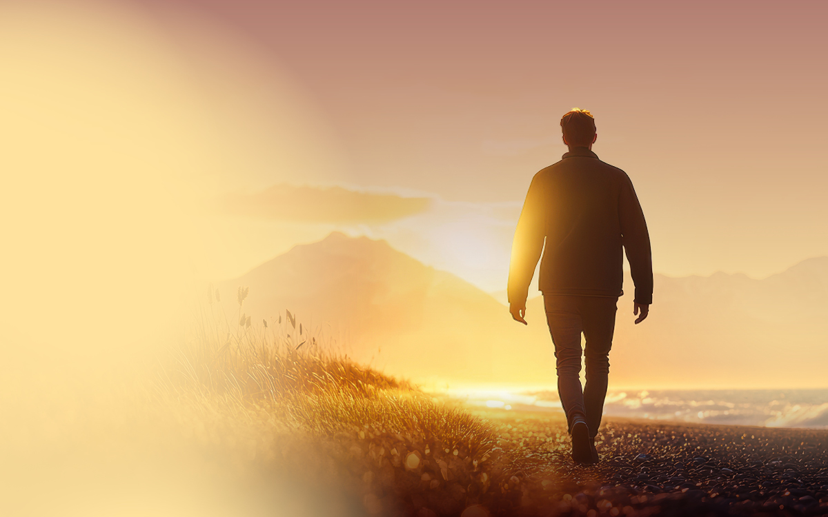 Silhouette of a man walking towards a beautiful sunset 