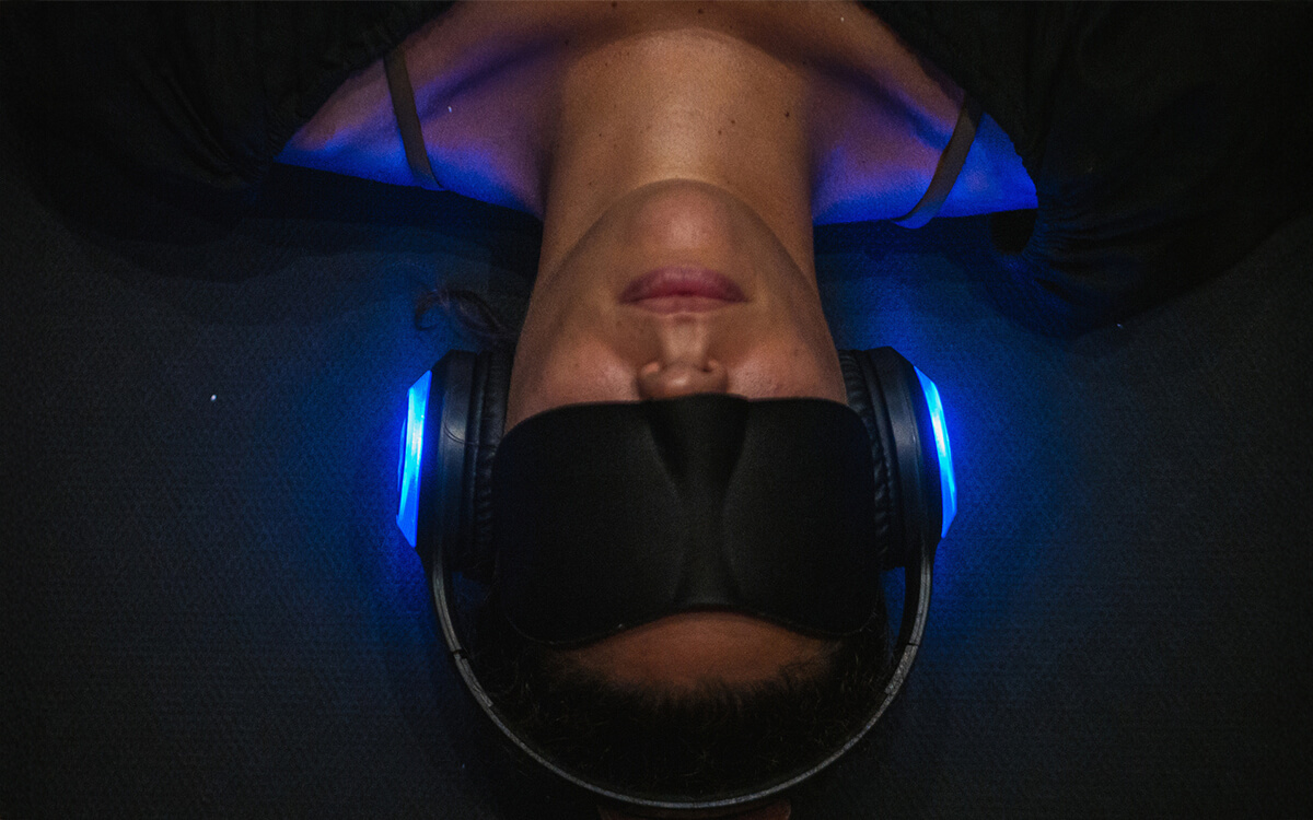Woman laying down wearing a blindfold and headphones