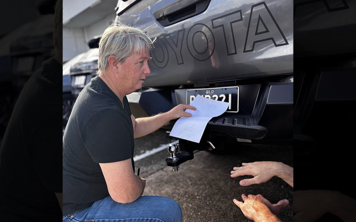 Man crouching behind a Toyota with a diagram