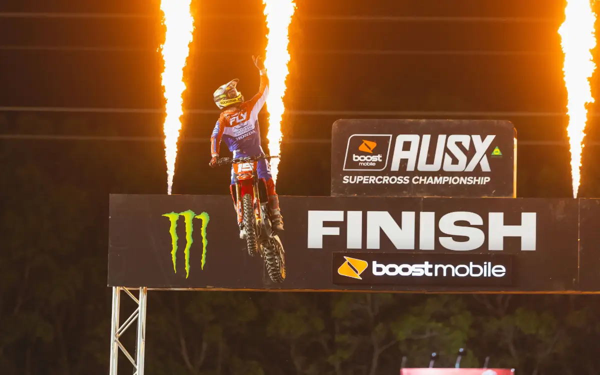 Motorbike rider at finish line with fire in background