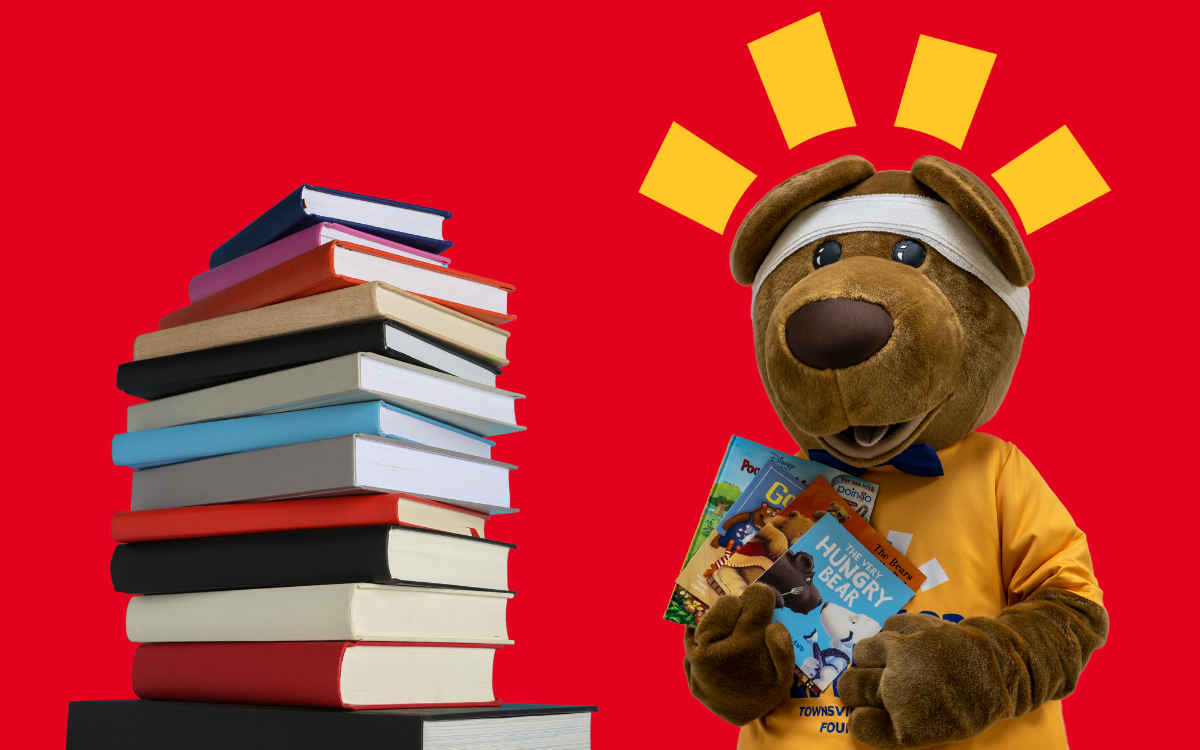 Brighter bear standing next to a pile of books